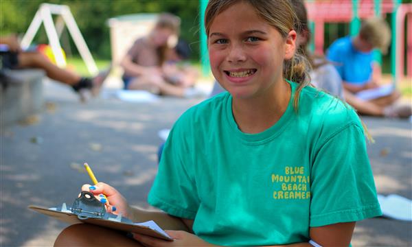 student smiles at camera while writing